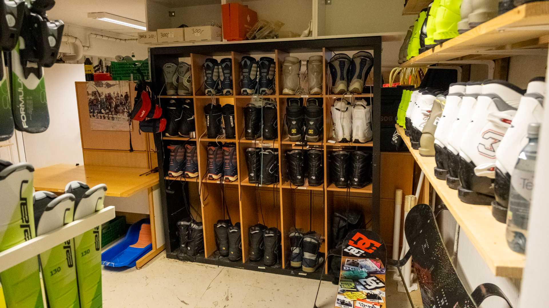 Rom med skiutleieutstyr: ski, snowboard og støvler står pent organisert på hyller for kunder.