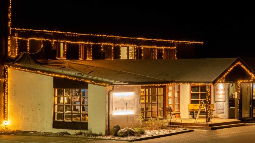 Utsmykket hotell inngang med julelys om natten på Rauland, skiltet Austbø Hotell og Raualand Feriesenter kan sees.