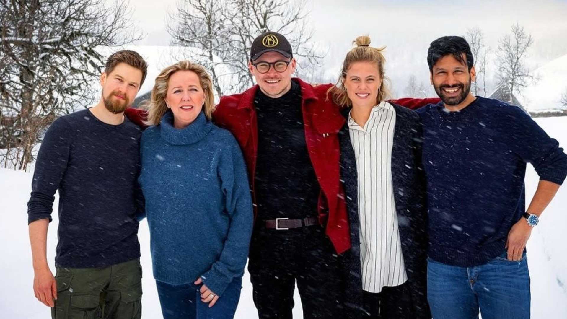 Jeg kan ikke identifisere personer på bildet, men fem personer smiler i snødekt landskap.