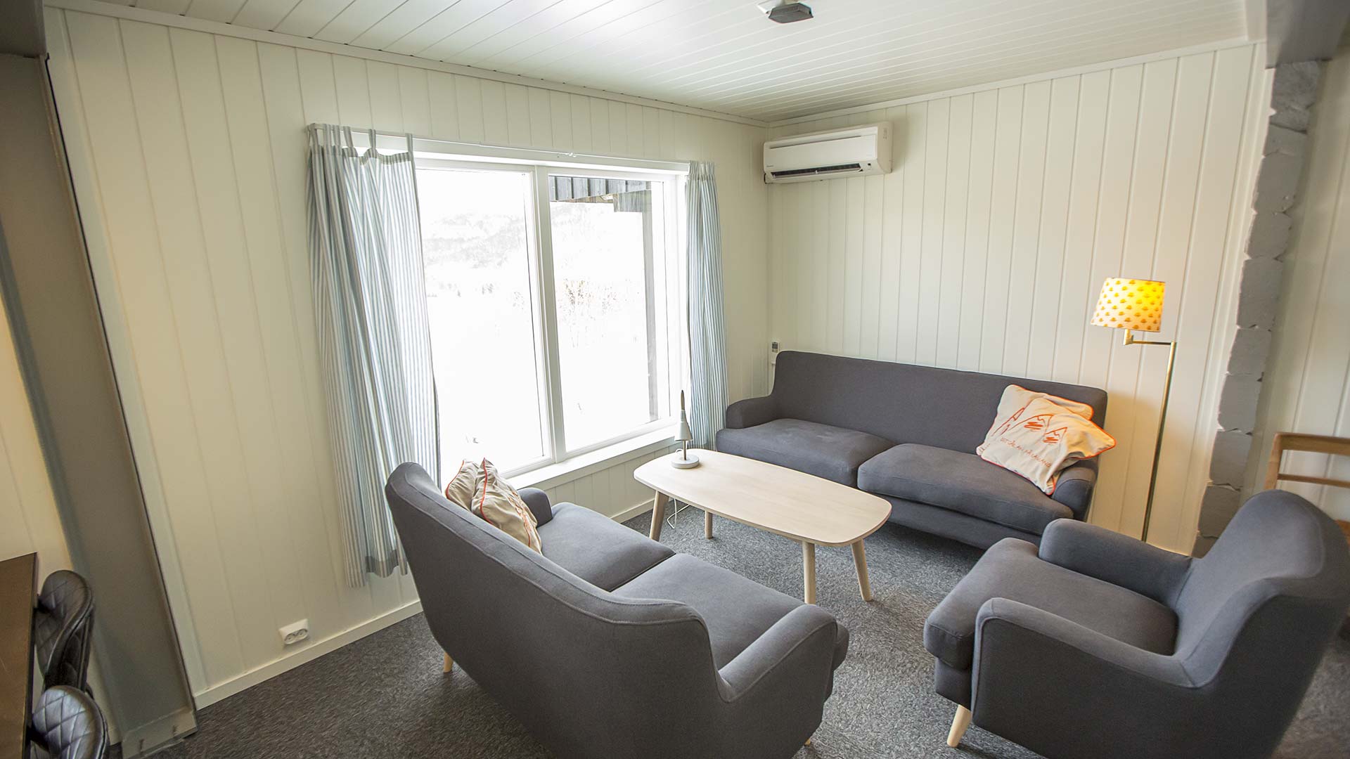 Lys stue med grå sofaer, bord og vindu med gardiner, moderne og komfortabelt interiørdesign.