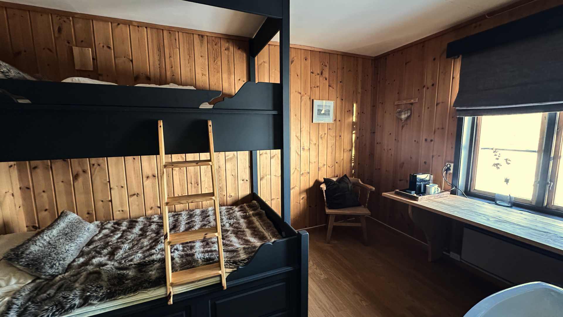 Koselig hytteinteriør med køyeseng, trepaneler og kaffekrok ved vindu. Perfekt for fjellferie.