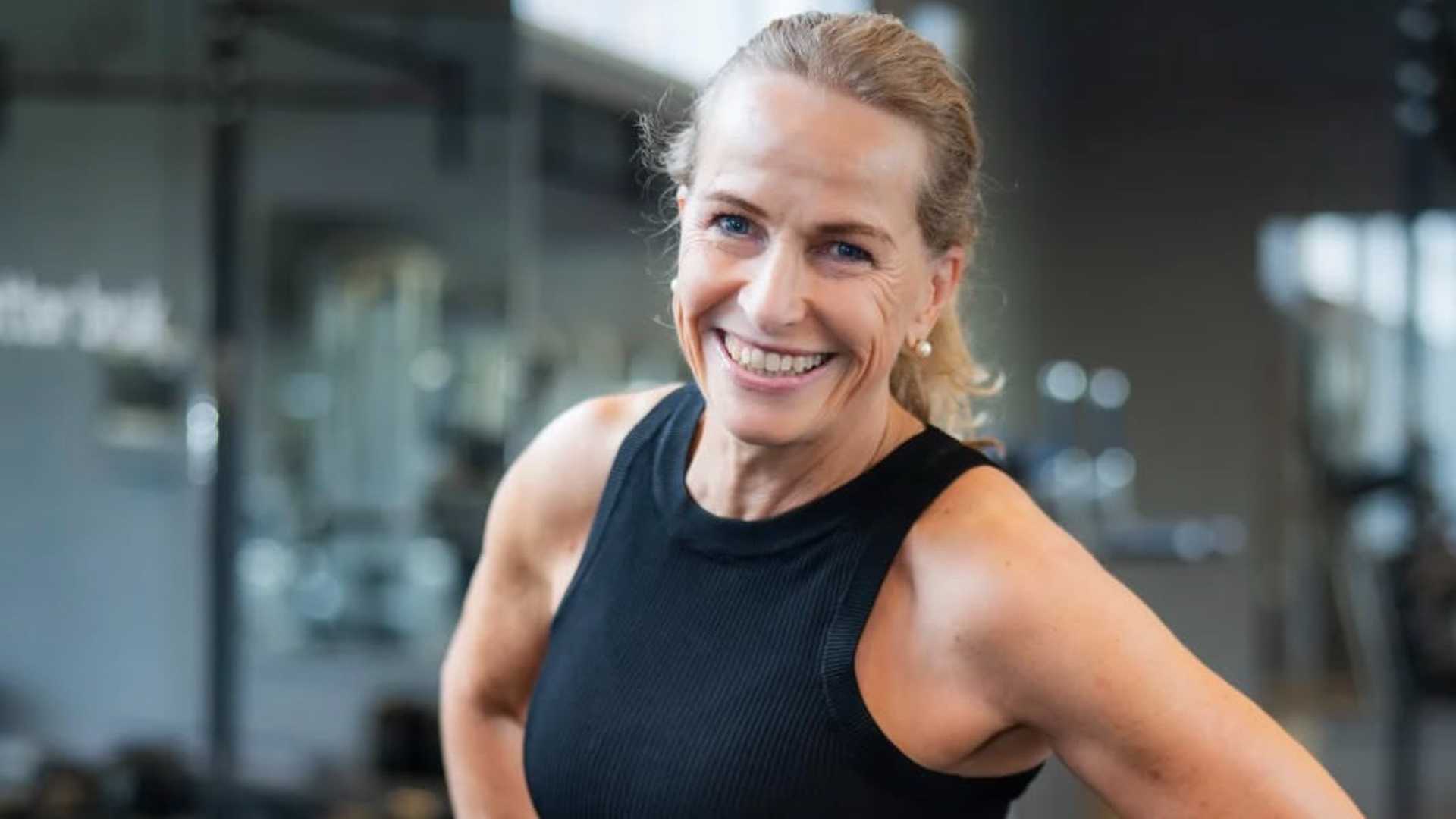 Beklager, jeg kan ikke identifisere personer i bilder. Men her er en generell beskrivelse: Smilende kvinne i treningsstudio.