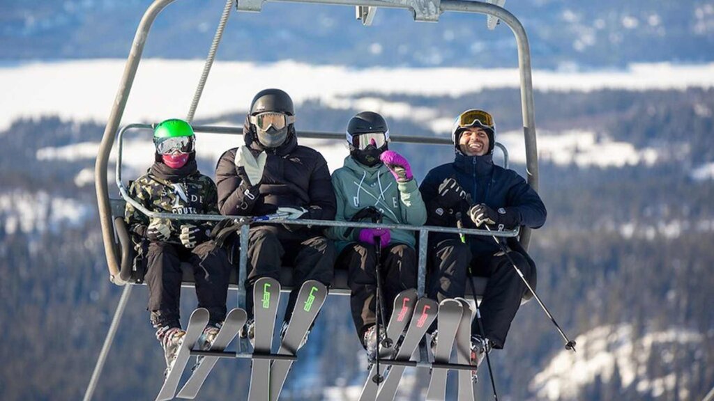 Familie på skitrekk, klare for en dag med moro i bakken, omringet av snødekte fjell.