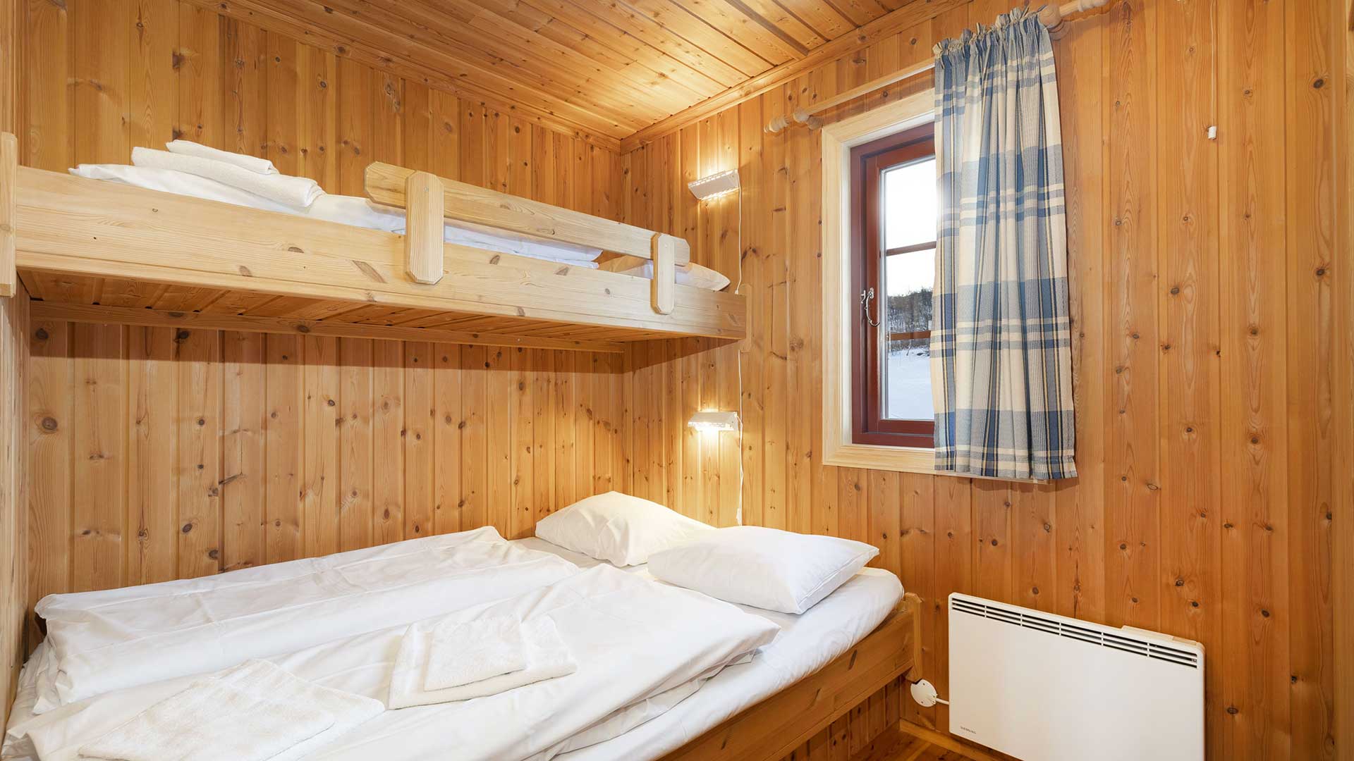 Koselig soverom med køyeseng i trepanel, vindu med rutete gardin. Perfekt for hyttetur i naturen.