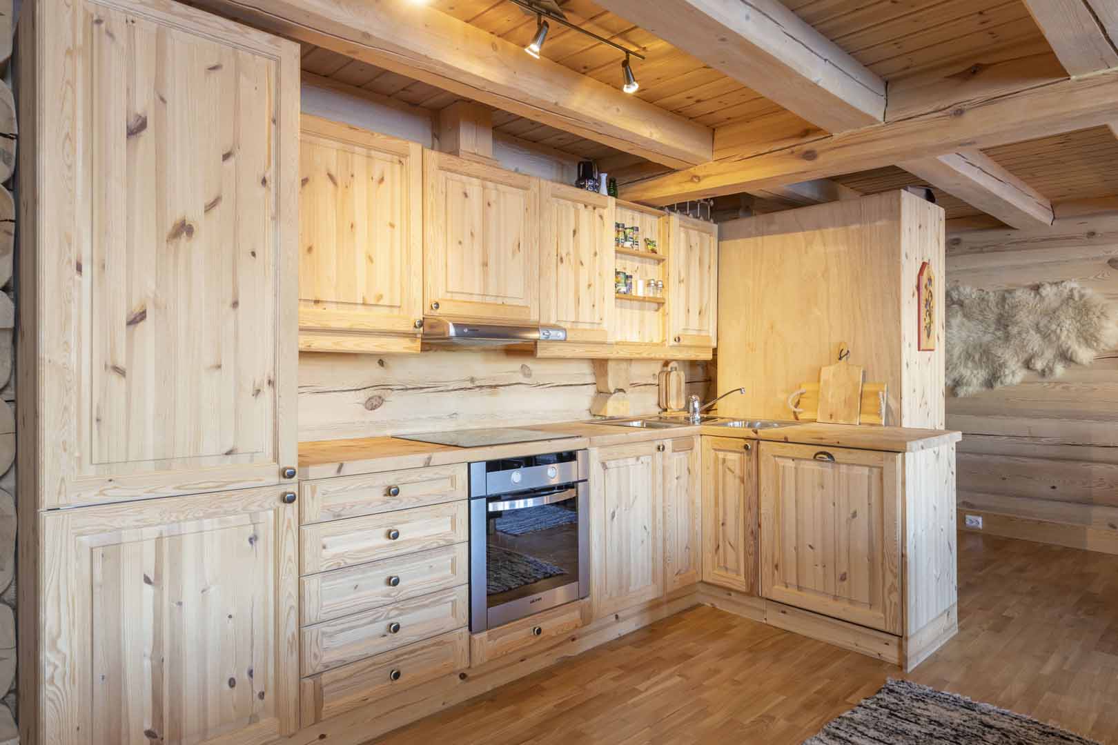 Moderne hyttekjøkken i tre med innebygd ovn, skapplass og belysning. Koselig og funksjonelt design.