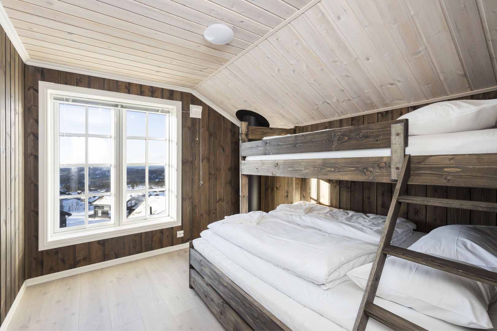 Soverom med køyeseng i tre, vindu med utsikt over vinterlandskap. Lyst og koselig interiørdesign.