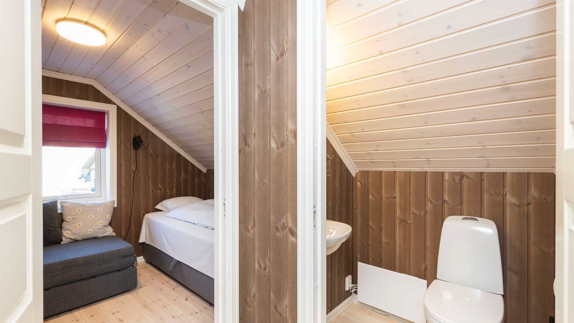 Moderne loftsrom med seng og bad, trepanel og naturlig lys. Koselig interiørdesign.