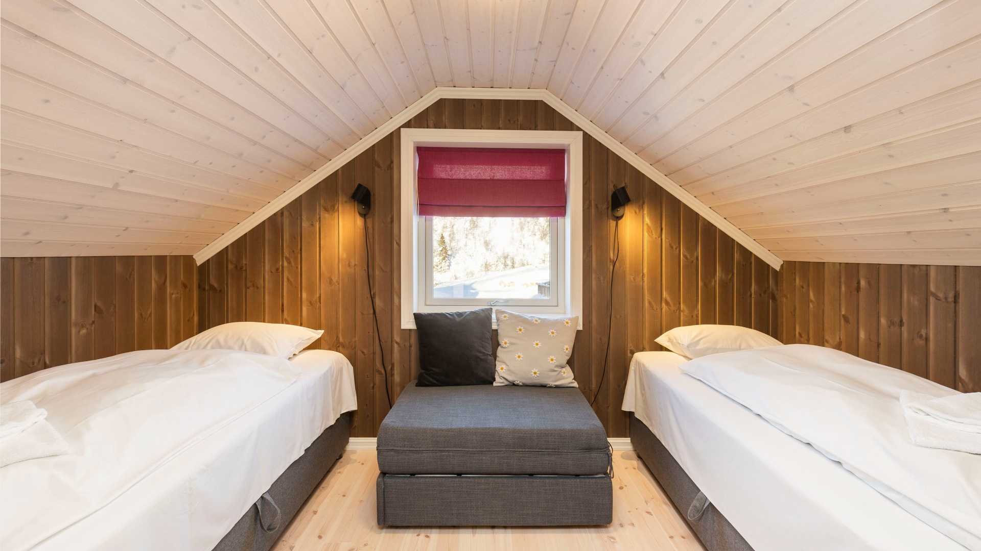 Koselig soverom med to enkeltsenger, en grå sofa og vindu. Perfekt for å slappe av i et moderne treinteriør.