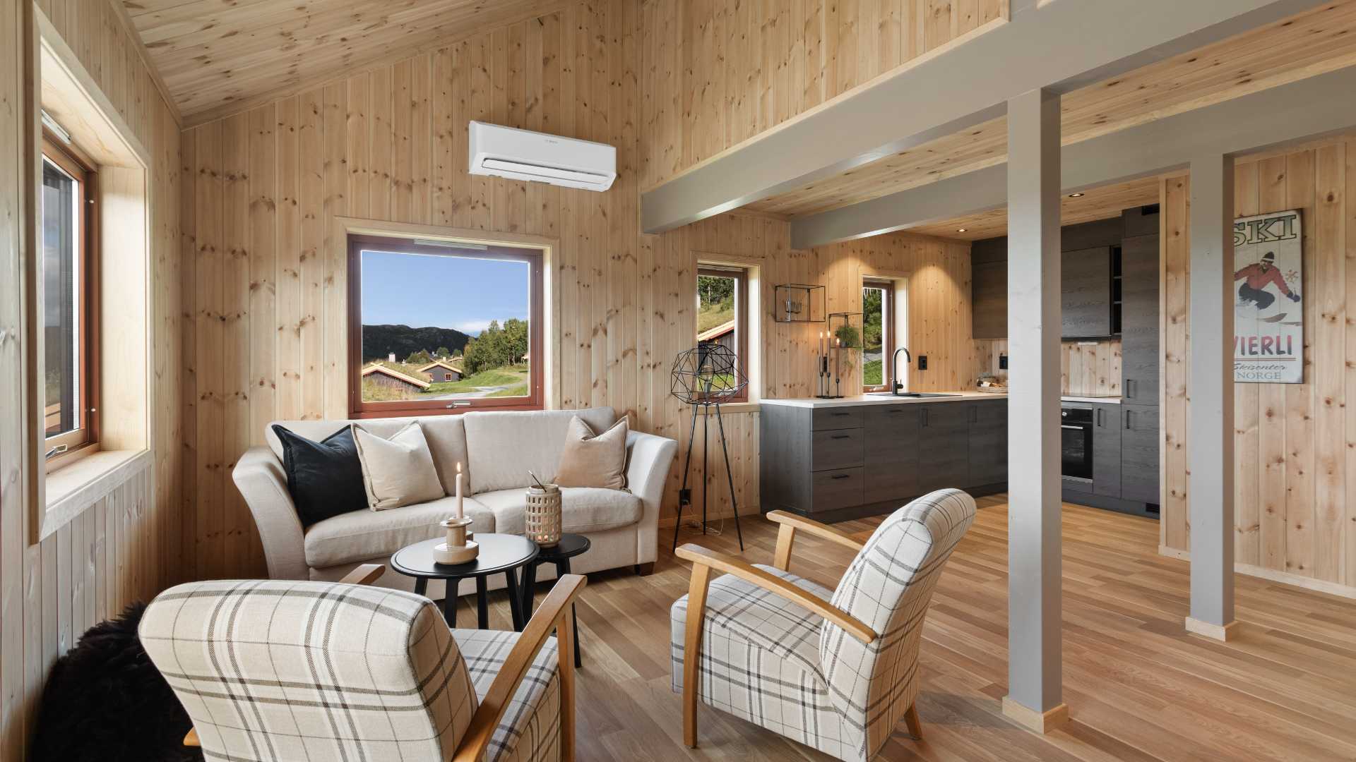 Moderne norsk stue med lyse trematerialer, komfortabel sofa, vinduer med utsikt- hytteinteriør.