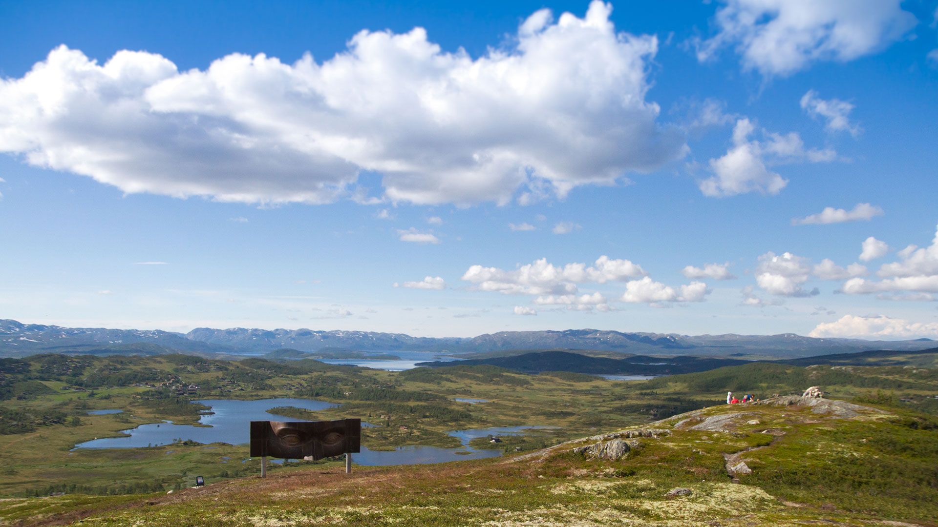 Utsikt over fjellandskap med blå himmel og skulptur i forgrunnen, Hallingdal, Norge.