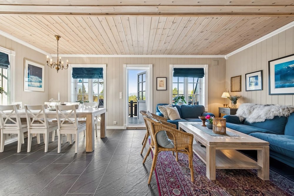 Lyst og koselig stueinteriør med spisebord, sofagruppe og utsikt mot hagen. Skandinavisk stil.