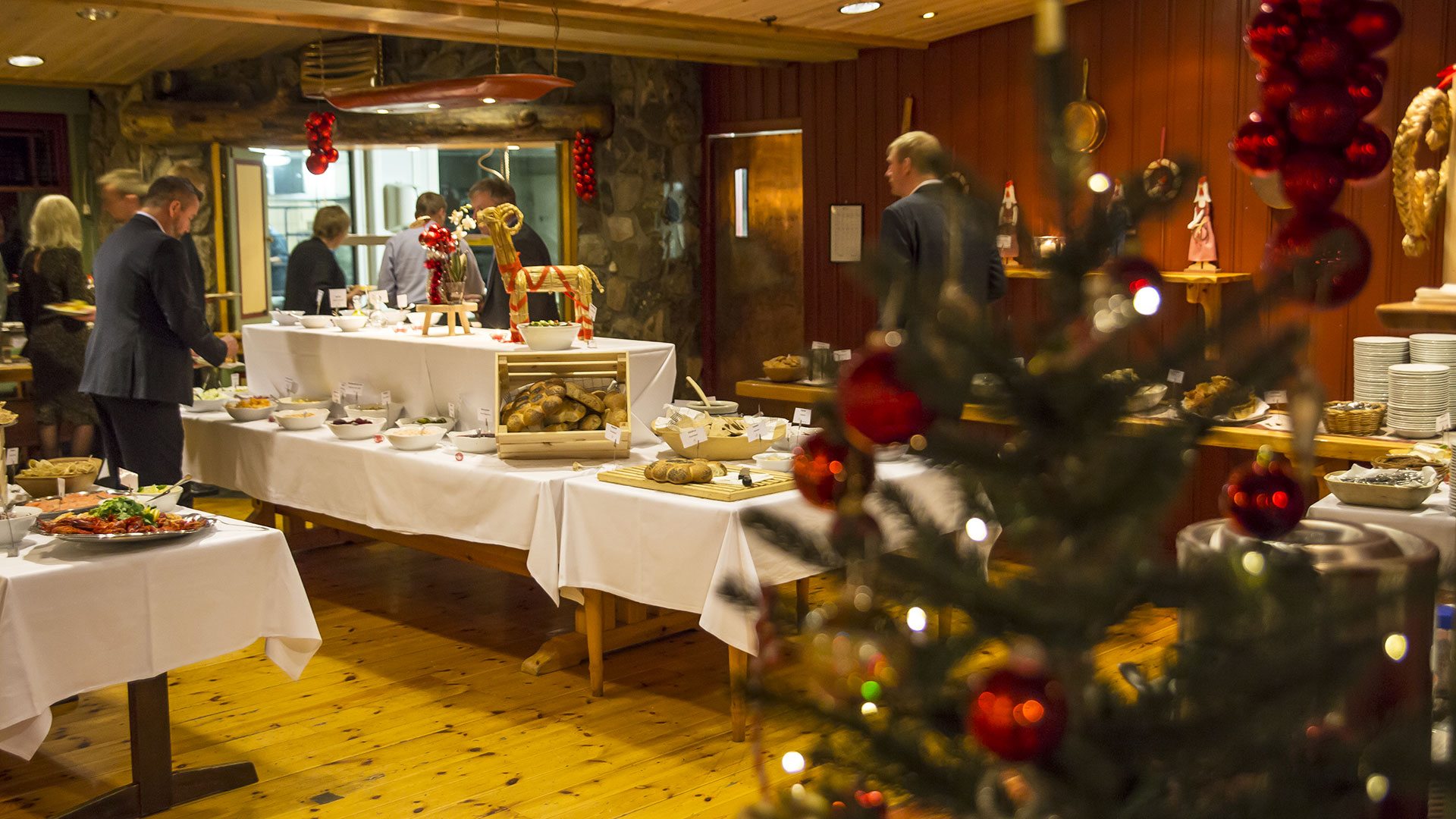 Julebuffet med tradisjonelle retter og festlige dekorasjoner i en koselig restaurantsetting.