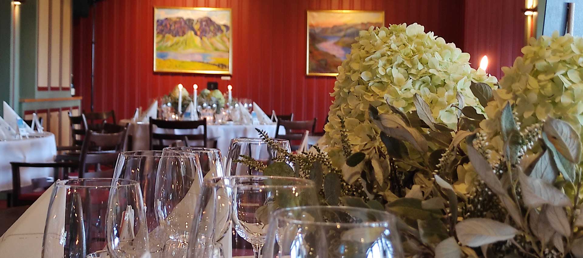 Elegant borddekking med blomster og vinglass i en stemningsfull restaurant.