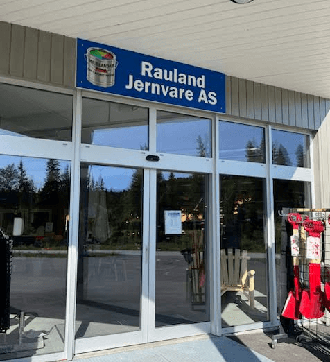 Inngang til Rauland Jernvare AS, en jernvarebutikk med utendørs utstilling av varer og skilt i Norge.