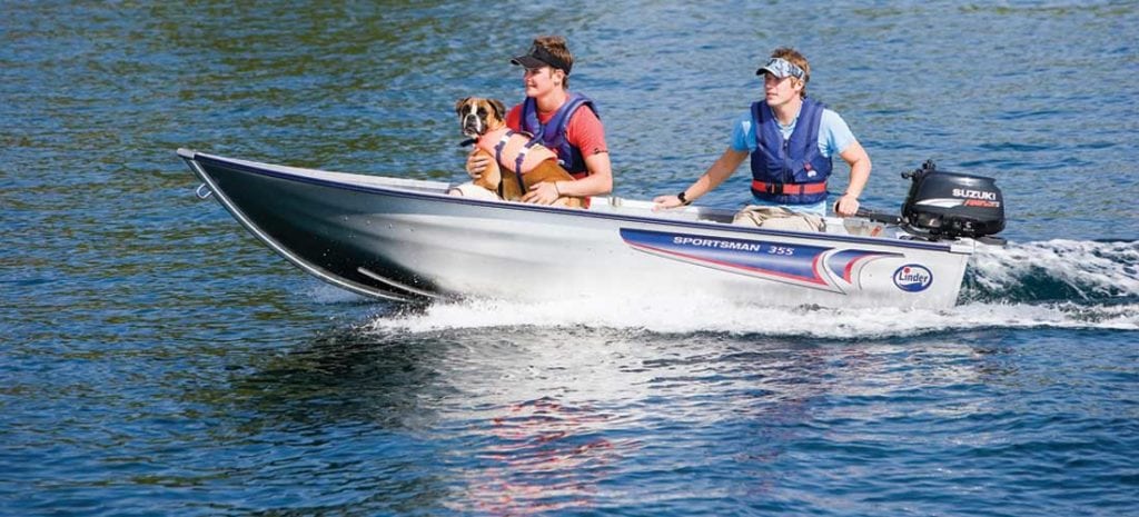 To menn og hund i en motorbåt på vannet, iført redningsvester.
