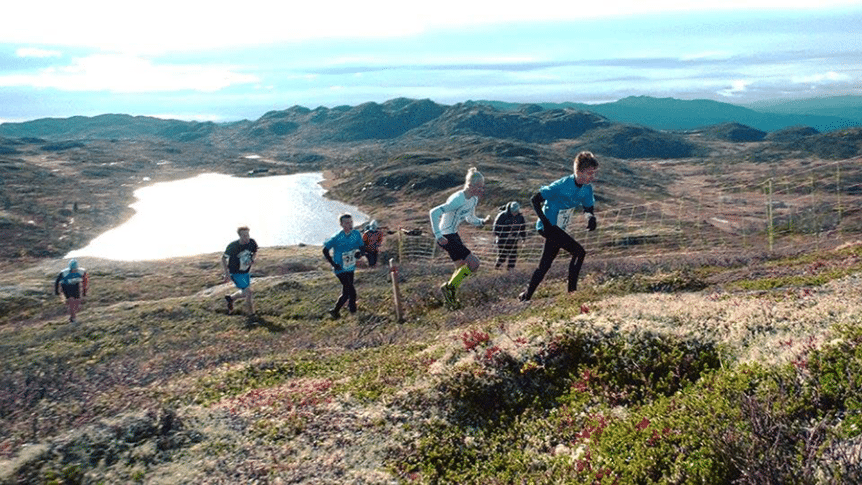 Løpere konkurrerer i fjellandskap ved innsjø.