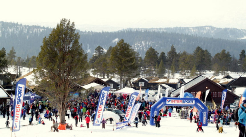 Folk samles på skiarrangement i snødekt landskap med Intersport-bannere, Norge.