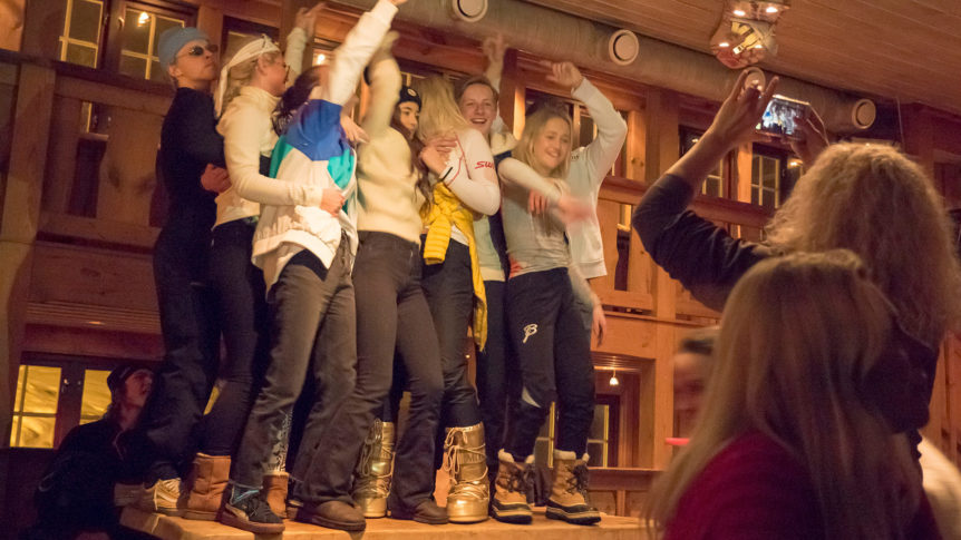 Gruppe mennesker danser på en trebjelke innendørs, i festlig stemning.