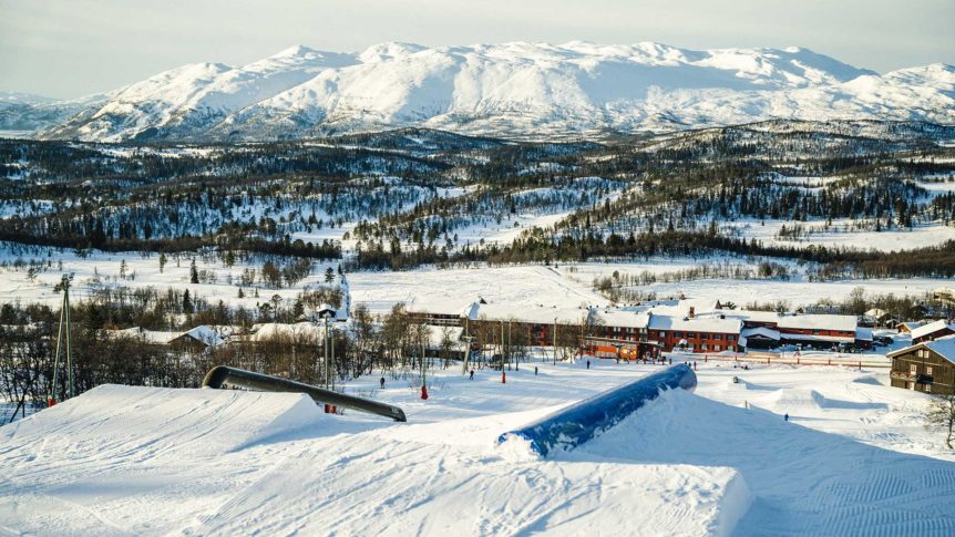 Snødekte fjell og alpinanlegg i vinterlandskap, perfekt for ski og snowboard i Norge.
