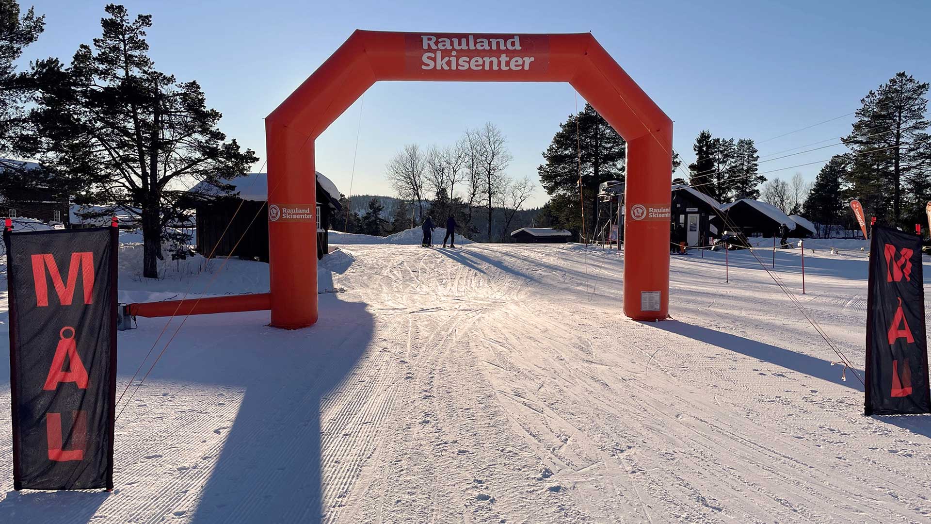 Målportal ved Rauland Skisenter en solrik vinterdag, omgitt av snødekt landskap og trær.
