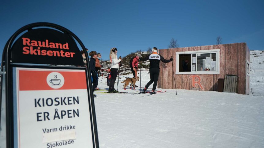 Skiere kjøper varm drikke fra åpen kiosk på Rauland Skisenter under solfylt vintervær.