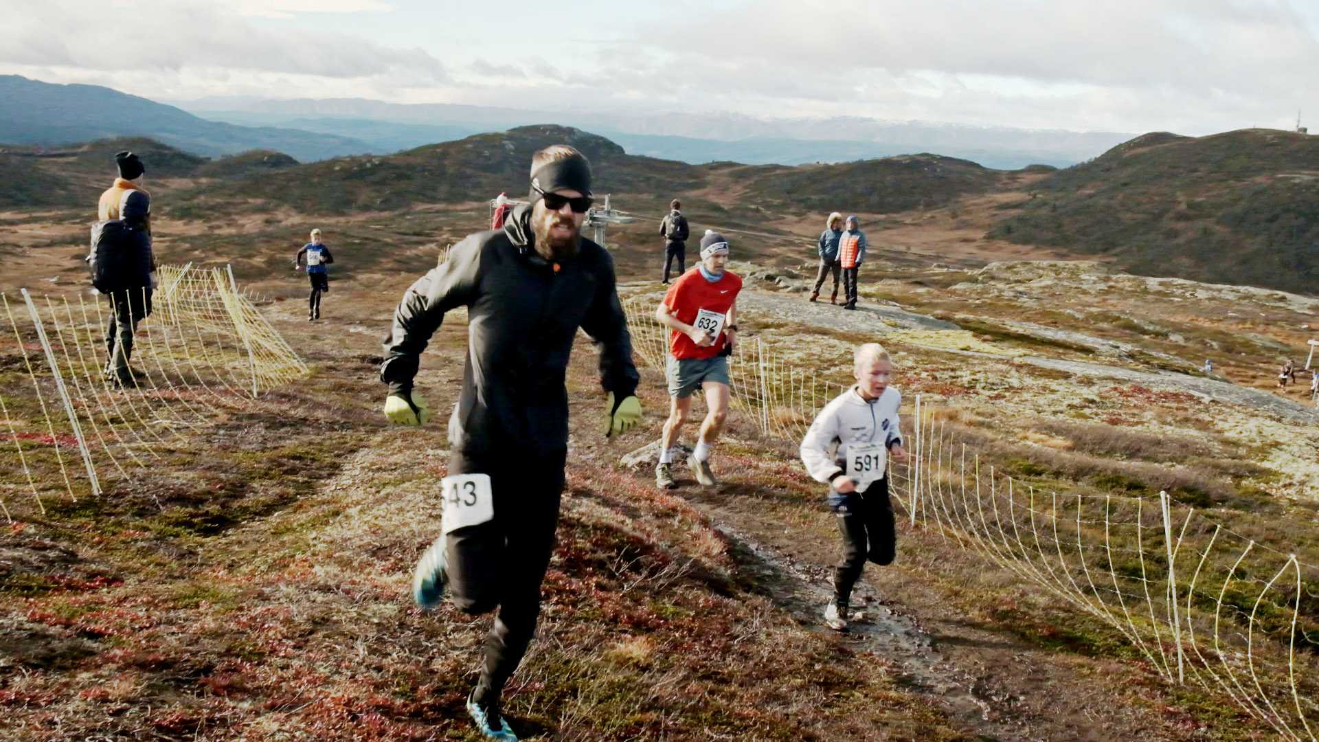 Løpere konkurrerer i fjellmaraton med vakker, vidstrakt utsikt i bakgrunnen.