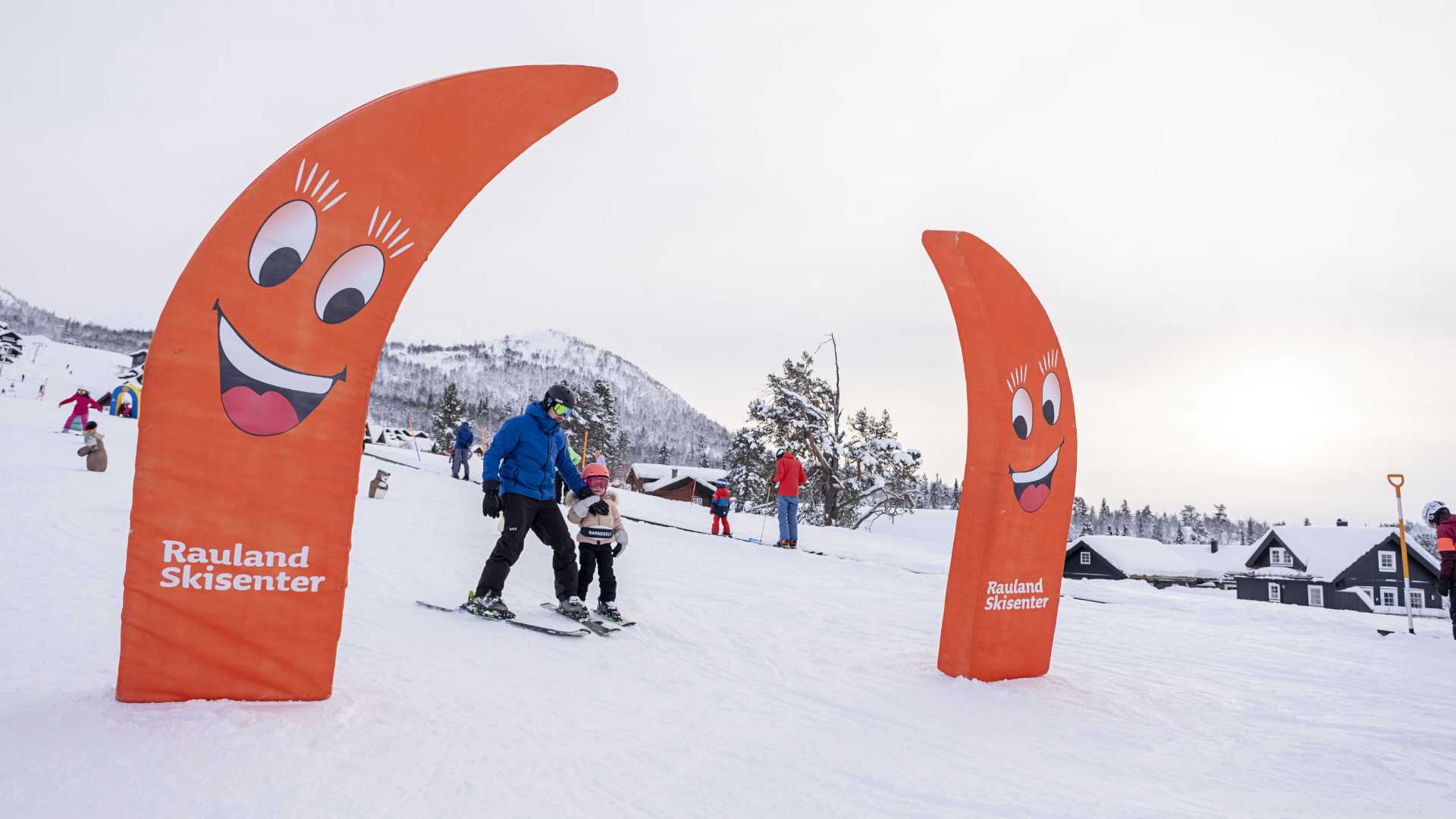 Familie som står på ski ved Rauland Skisenter, omgitt av snø og glade dekorasjoner.