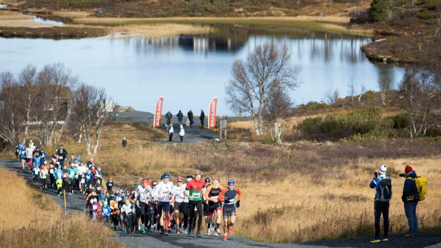Løpere deltar i terrengløp ved innsjøen Rauland en solrik dag om høsten.