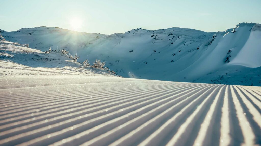 Nypreparert skiløype i solfylt vinterlandskap, med snødekte fjell i bakgrunnen.