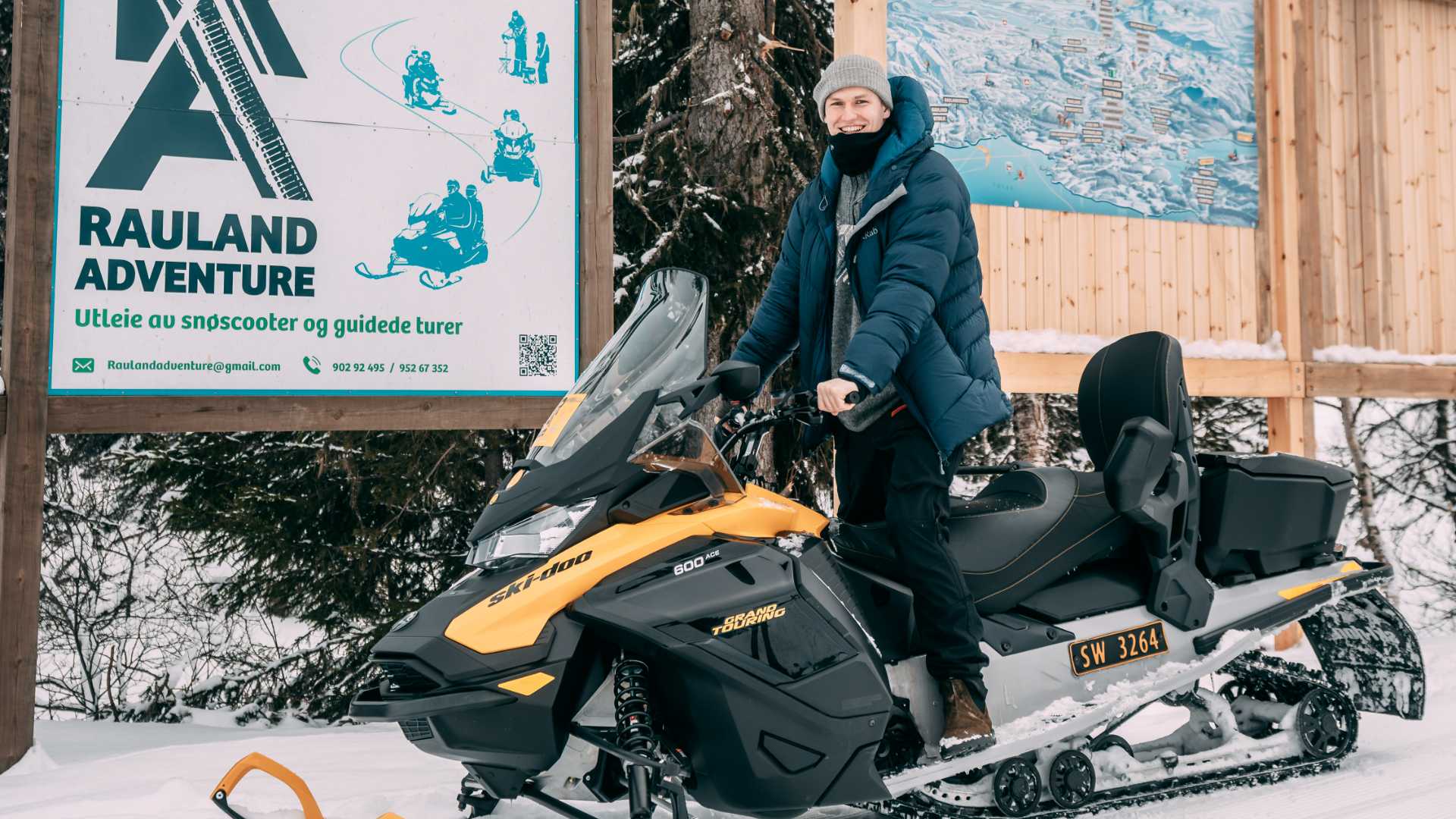 Person på snøscooter foran Rauland Adventure-skilting, klar for leie og guidede turer i vinterlandskap.