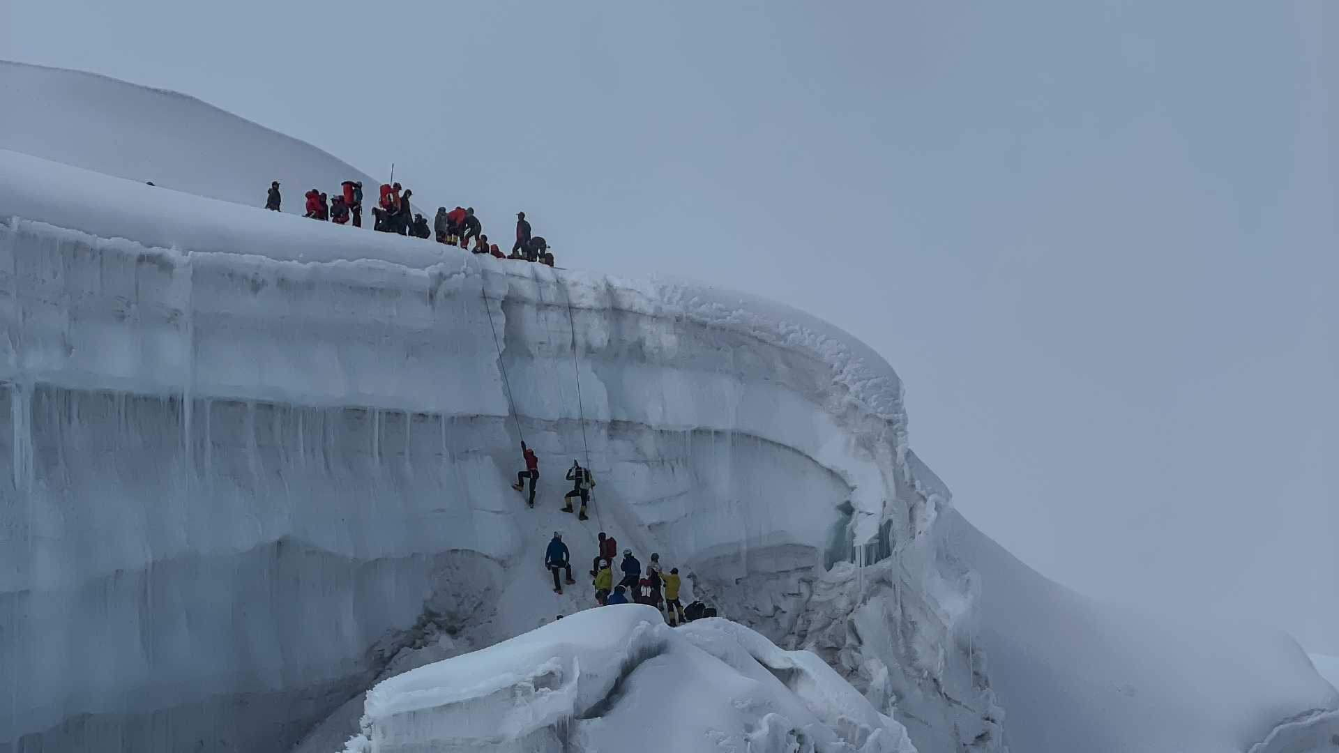 Klatrere på en snødekt fjellskrent under vinterforhold. Eventyrlystne på isklatring i kalde omgivelser.