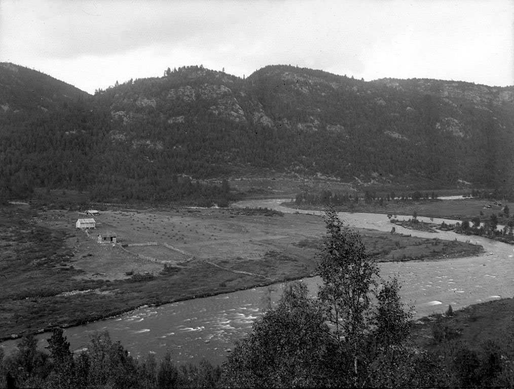 Elv og dal med fjell i bakgrunnen, landskap i svart-hvitt, landlig gård i Norge.