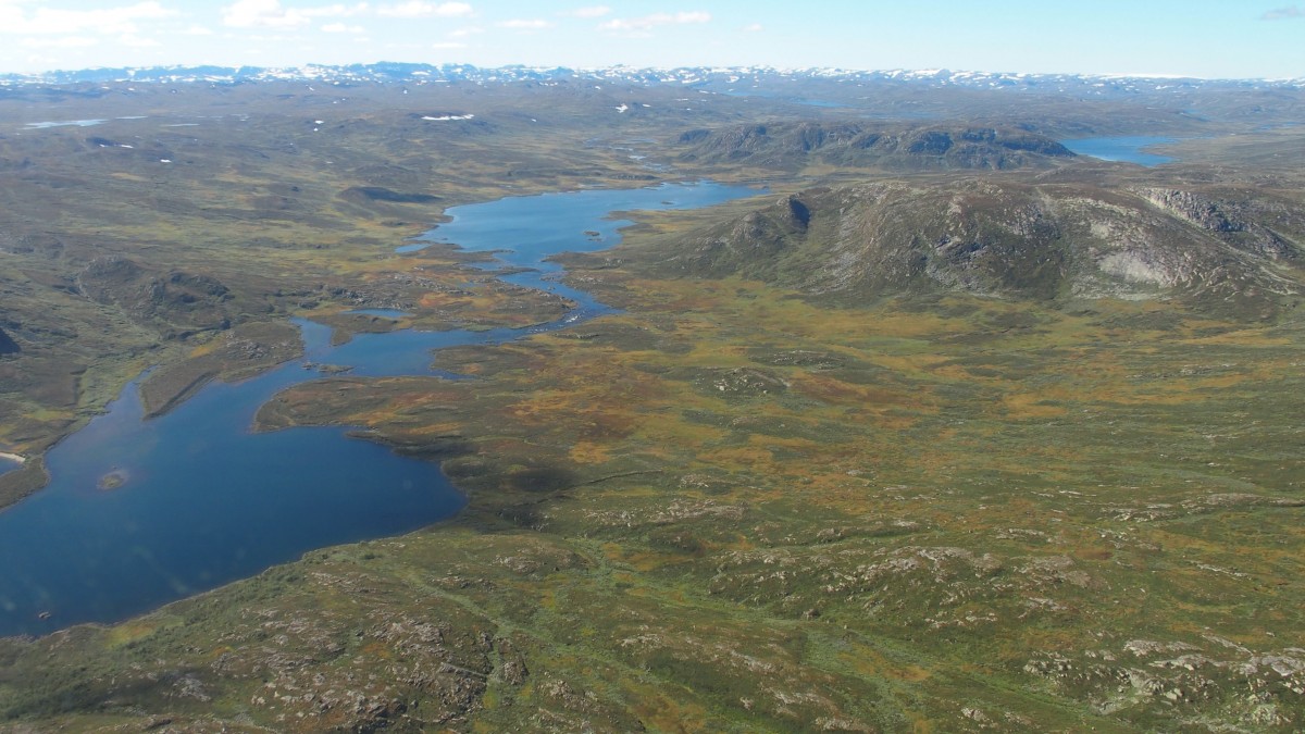Luftfoto av norsk fjellandskap med innsjøer og fjell, under blå himmel. Perfekt for natur- og villmarksopplevelser.