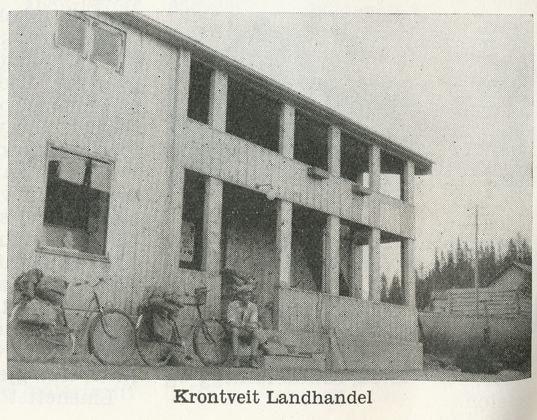 Svart-hvitt bilde av Krontveit Landhandel, en toetasjes bygning med sykler foran.