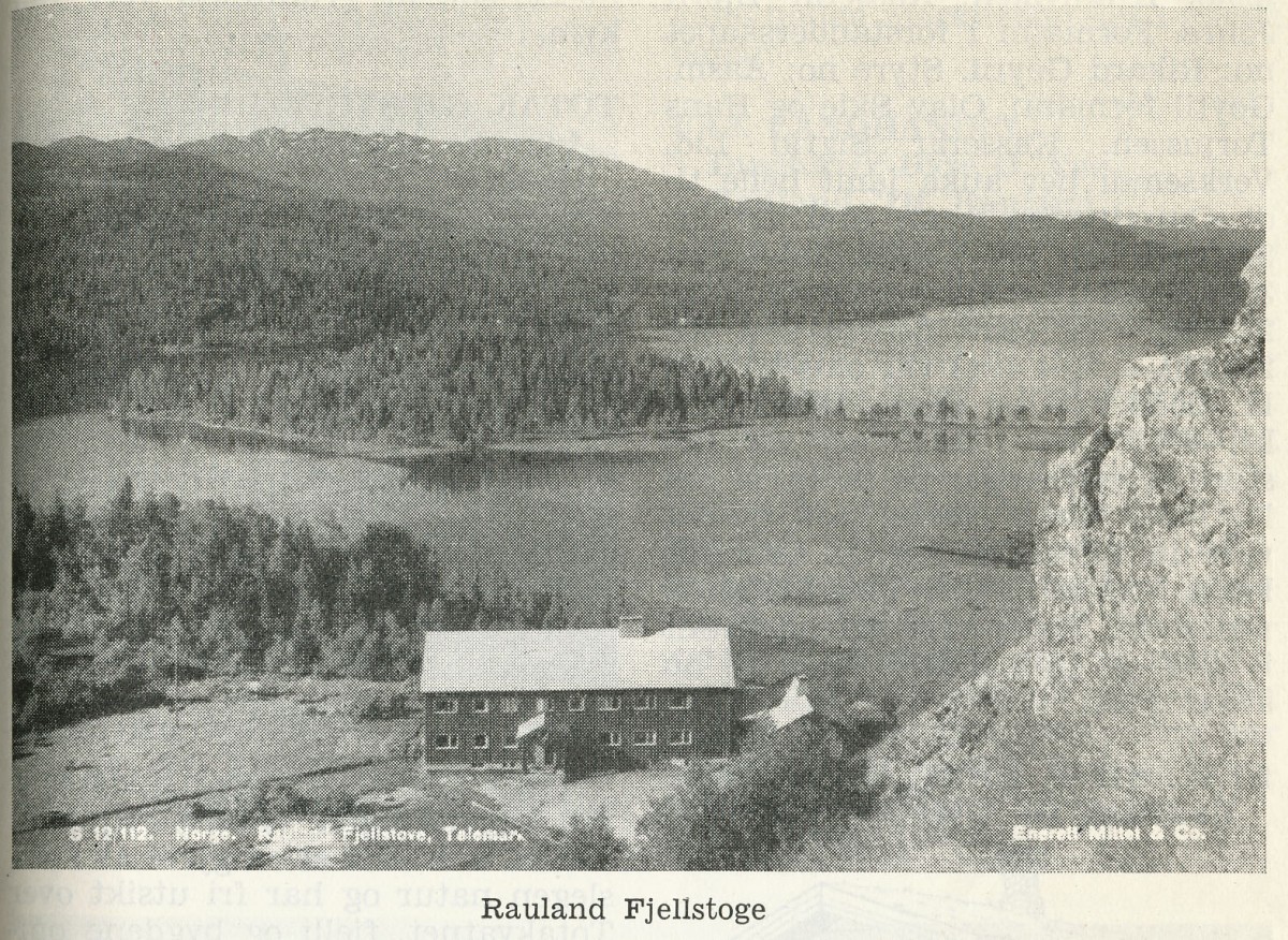 Sort-hvitt bilde av Rauland Fjellstoge ved innsjø, omgitt av skog og fjell i Telemark, Norge.