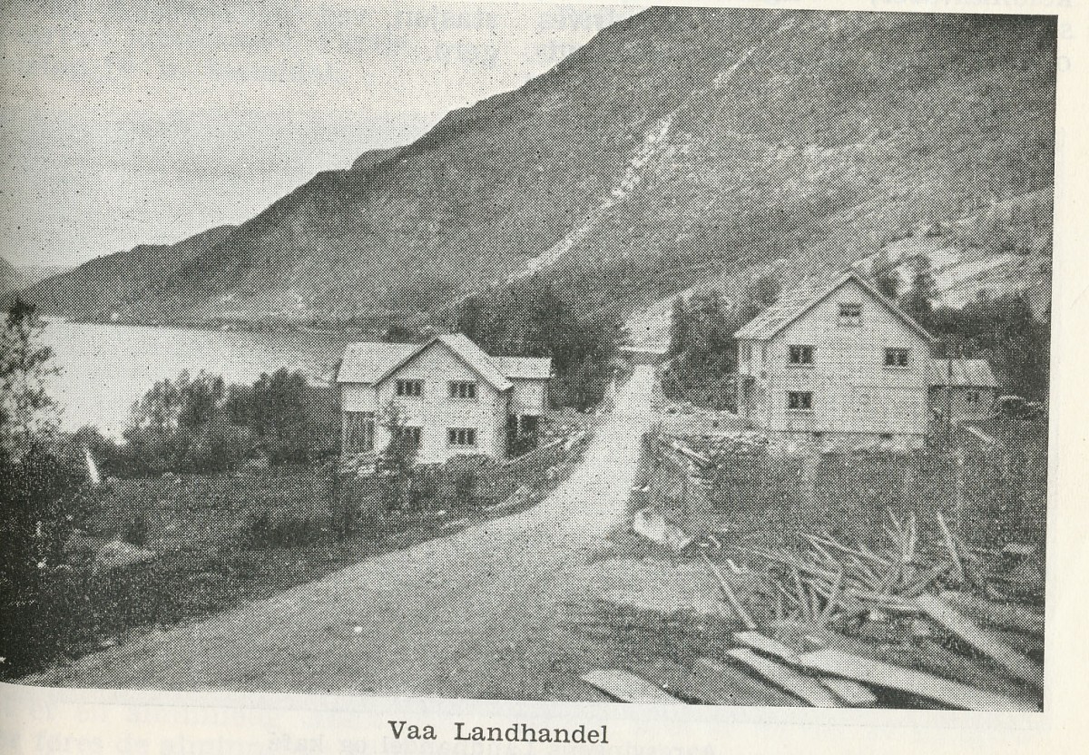 Gammelt foto av Vaa Landhandel med fjell og vann i bakgrunnen, viser rural norsk landsbygd.