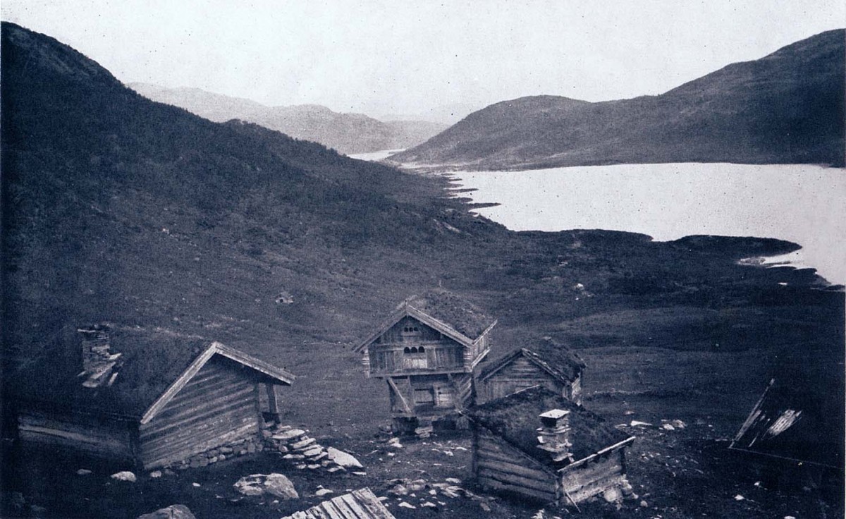 Gamle trehytter ved en innsjø i norsk fjellandskap, tidlig morgenstemning.