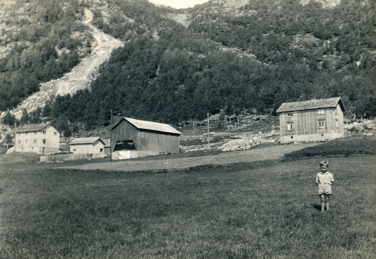 Gammelt bondegård med fjellbakgrunn, barn i forgrunnen, landskap Norge.
