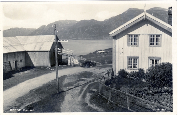 Gårdshus i Raundalen, Norge, med fjell og vann i bakgrunnen. Nostalgisk svart-hvitt bilde av norsk landskap.