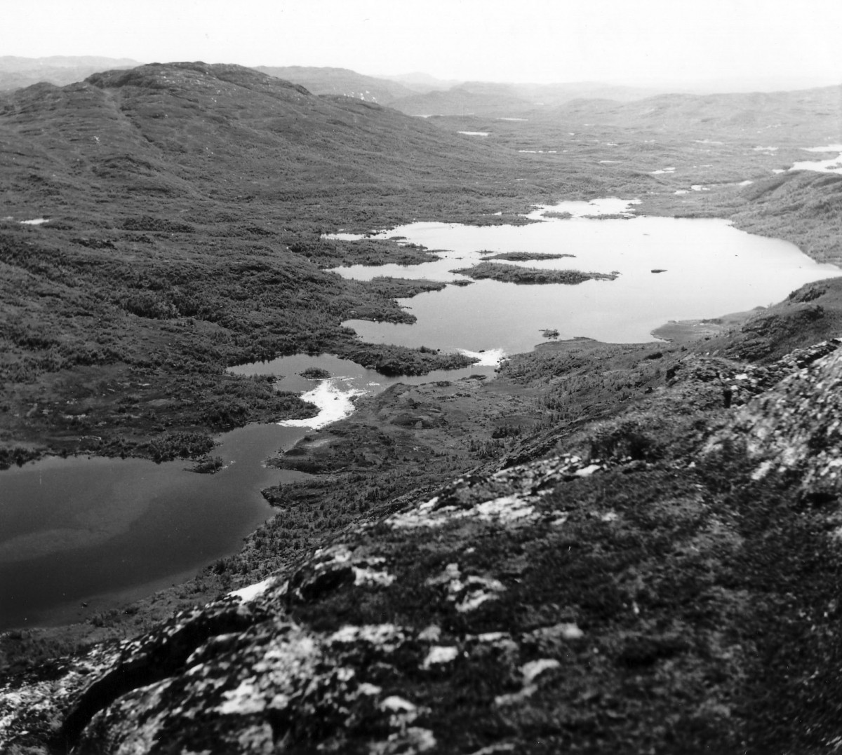 Svart-hvitt landskap av fjellområde med innsjøer, skog og vidstrakt dal i Norge.