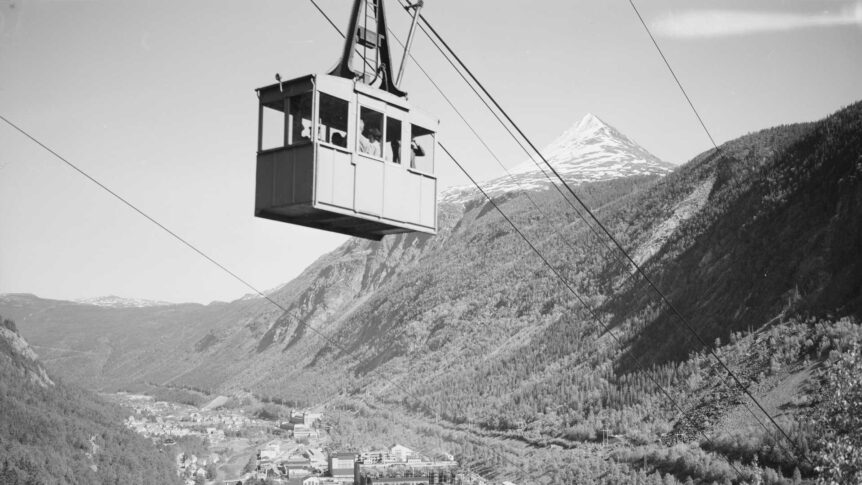Taubane over norsk fjordlandskap med snøkledd fjell i bakgrunnen. Turistattraksjon i naturskjønne omgivelser.