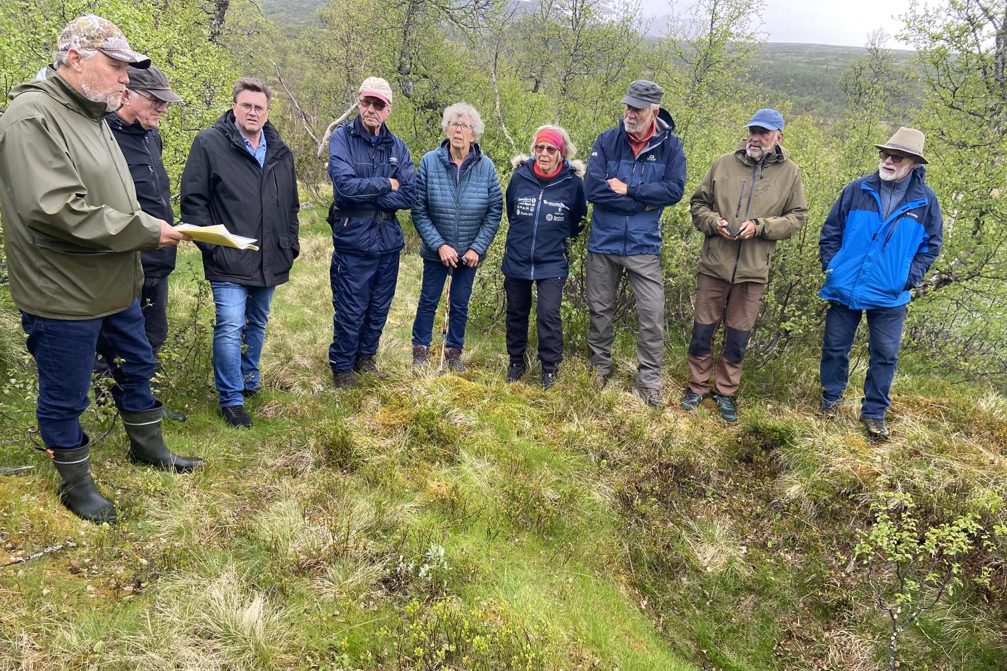 Gruppe samlet i norsk skog for utendørs møte, omkranset av grønn natur.