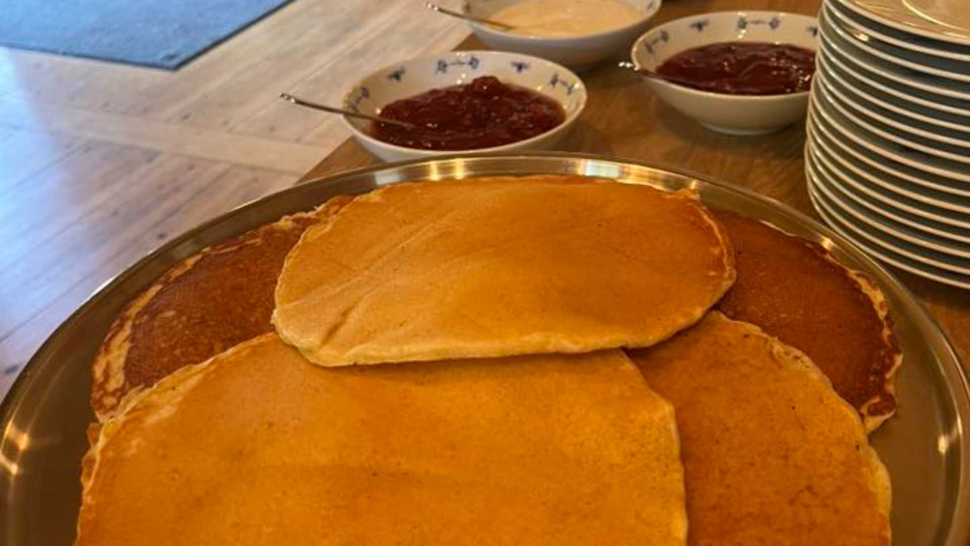 Pannekaker og syltetøy servert på et bord med fat og skåler med deilig pålegg.