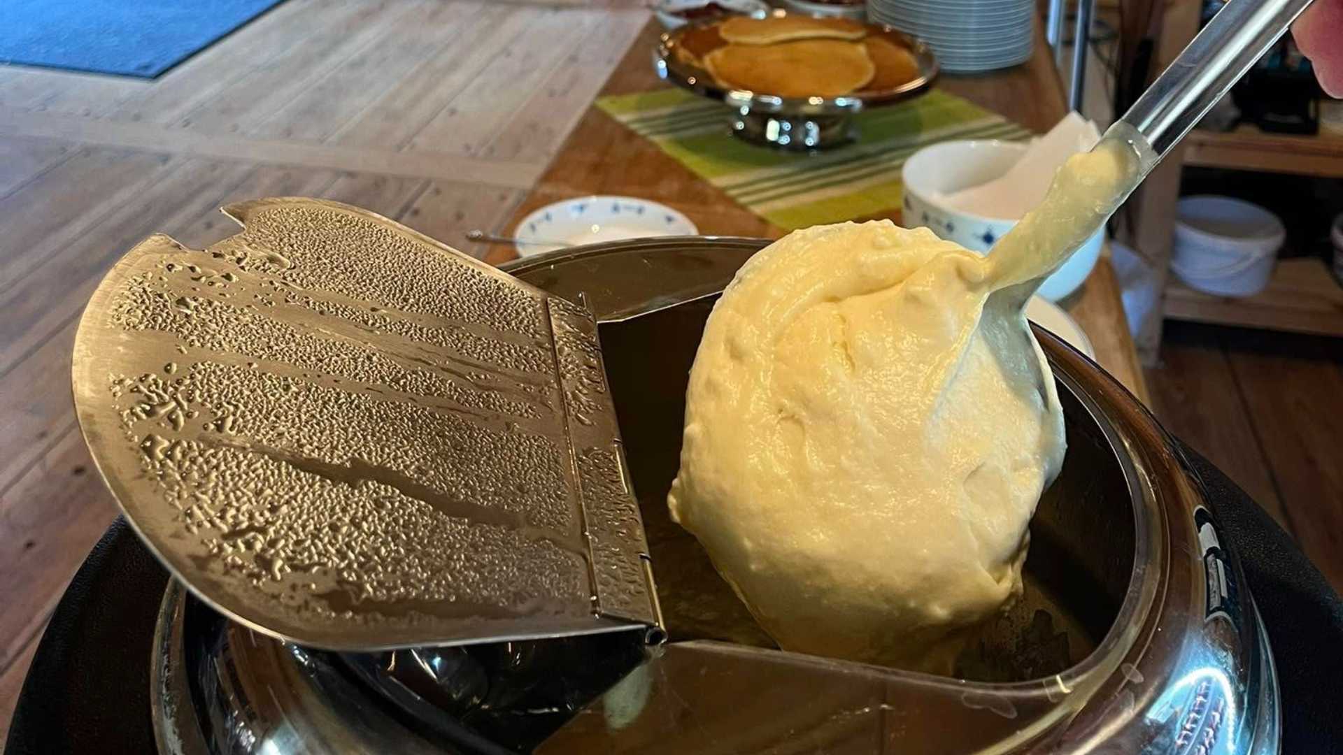 Tradisjonell norsk rømmegrøt serveres varm i gryte, klar for måltid.