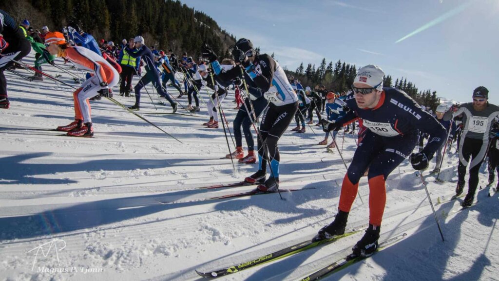 Deltakere i turrenn på ski i solfylt vinterlandskap, klare for konkurranse.