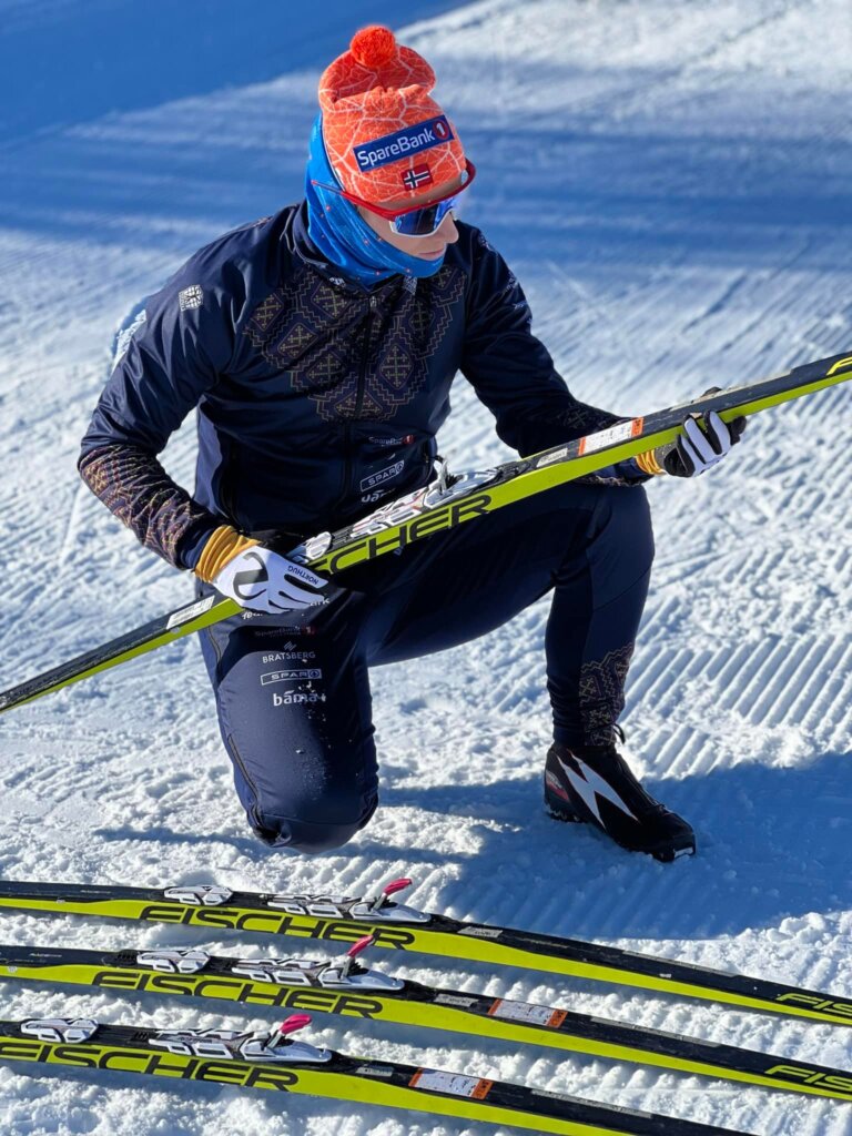 Beklager, jeg kan ikke identifisere personer i bilder. Her er et alt-tekstforslag for bildet:Person tester langrennsski på snø, iført fargerik lue og skidress.