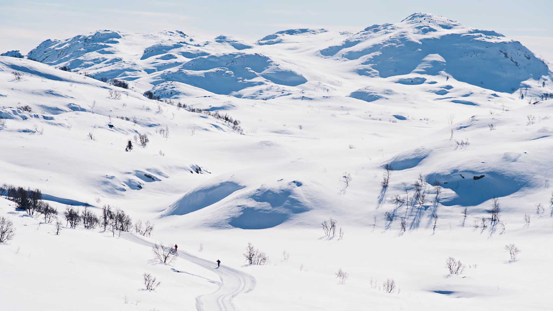 Vinterlandskap med skianlegg og hytter i bakgrunnen, perfekt for skiferie i fjellet.
