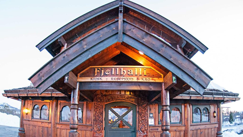 Tradisjonell norsk trebygning Fjellhalli med skilt, om vinteren. Snødekte fjell i bakgrunnen.