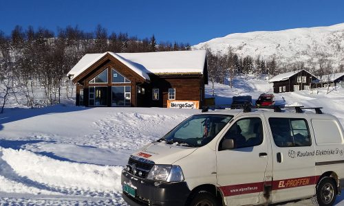 Hytte i snødekket norsk landskap med varebil fra Rauland Elektriske.