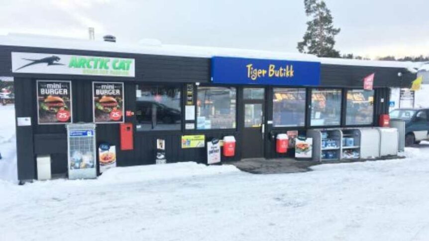 Utvendig fasade av Tiger Butikk med reklame for burgere, vinterlandskap rundt.